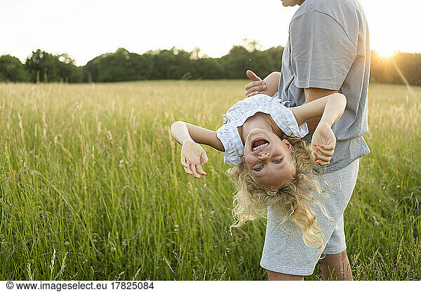 Mature man carrying cheerful daughter enjoying at field