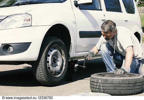 Mature man changing car tires  top view