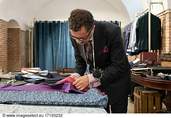 Mature man choosing fabrics in studio