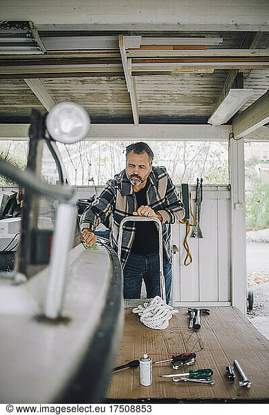 Mature man cleaning speedboat in garage