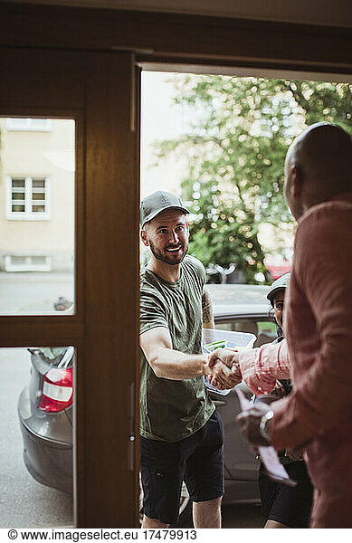 Mature man doing handshake with male technician at doorway