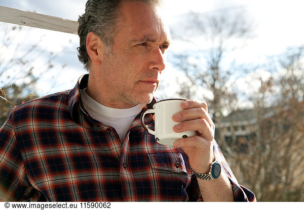 Mature man drinking from cup outside