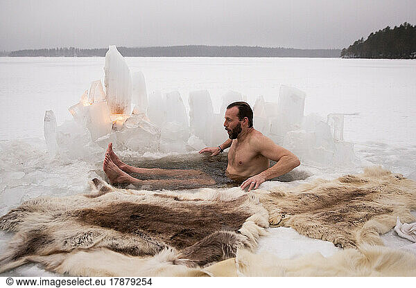 Mature man enjoying ice bath at frozen lake