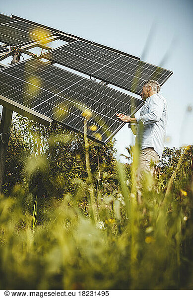 Mature man examining solar panels in garden