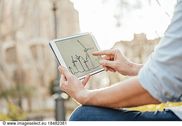 Mature man examining wind turbine diagram on tablet PC