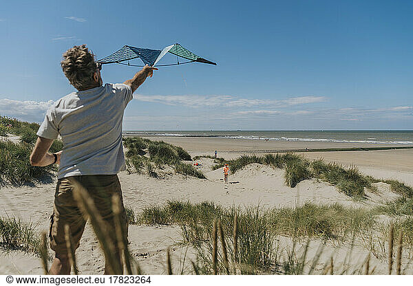 Mature man flying kite on sunny day at beach