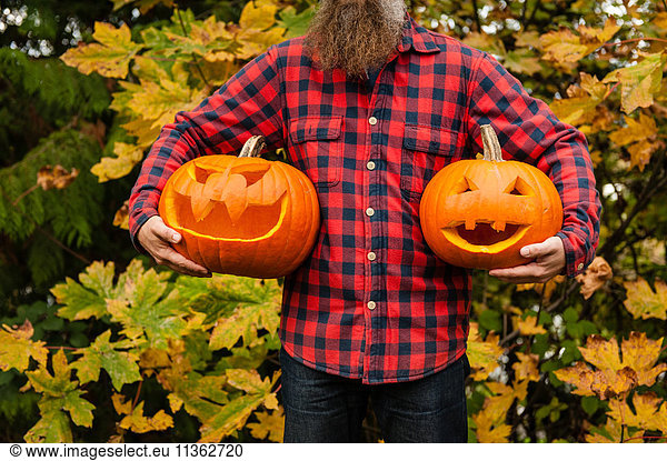 Mature man holding carved pumpkins