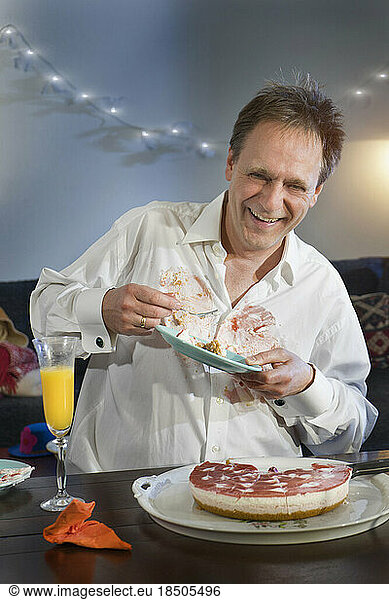 Mature man holding plate of cake accidentally spilt on shirt