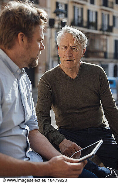 Mature man holding tablet PC and talking with father