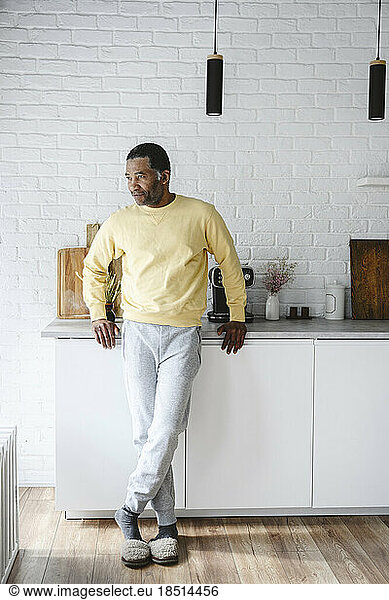 Mature man leaning on kitchen counter at home