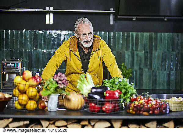 Mature man looking at vegetables and fruits on kitchen counter