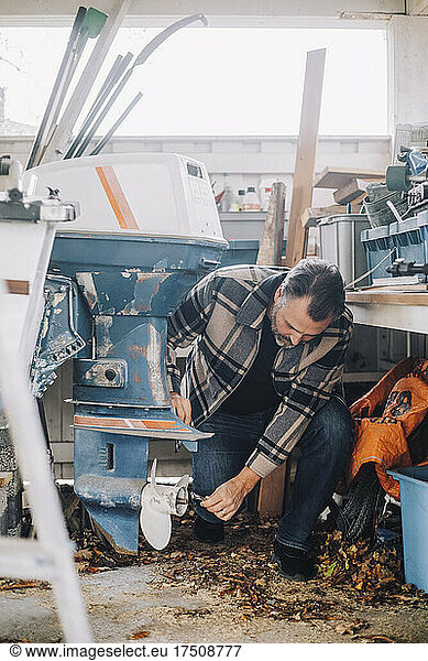 Mature man repairing nautical vessel in garage