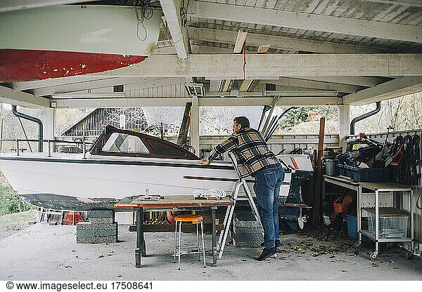 Mature man repairing speedboat in garage