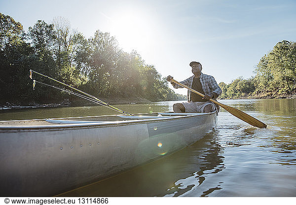 Mature man rowing on lake against sky