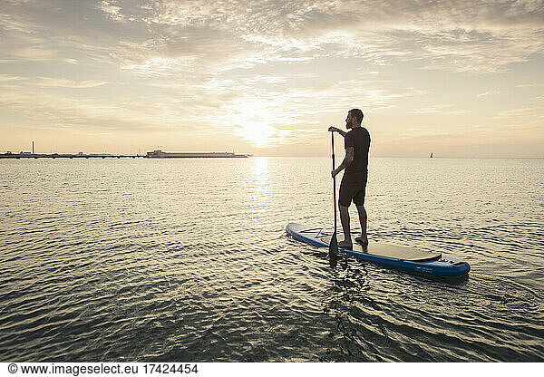 Mature man rowing paddleboard in sea