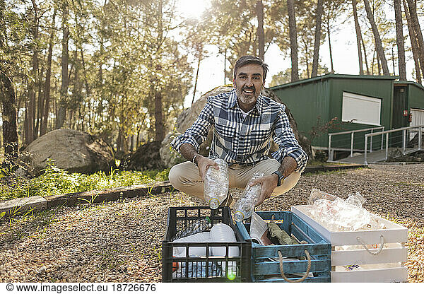 Mature man separating waste into crates in garden