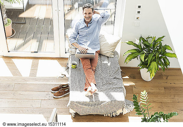 Mature man sitting on couch using laptop