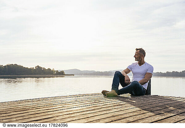 Mature man sitting on jetty at lake