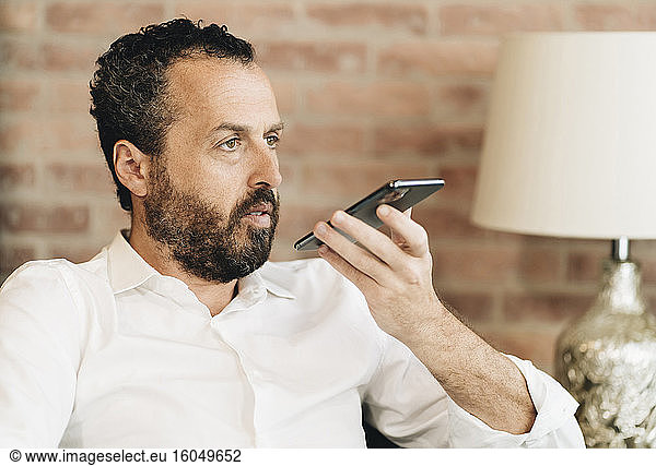 Mature man speaking voice mail in smartphone