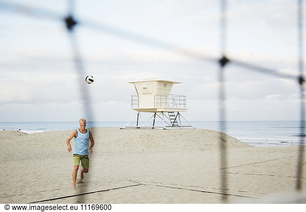 Mature man standing on a beach  playing beach volleyball.