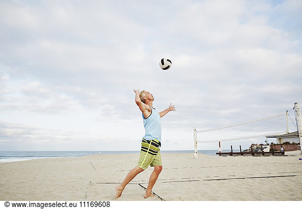 Mature man standing on a beach  playing beach volleyball.