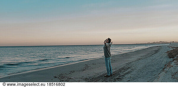 Mature man standing with arms outstretched at beach