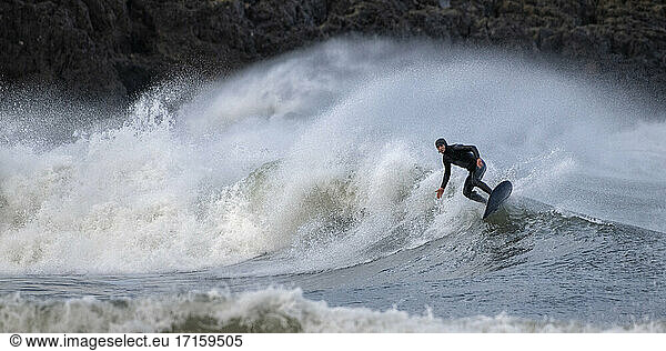 Mature man surfing on waves splashing in sea  Broad Haven South Beach  Wales  UK