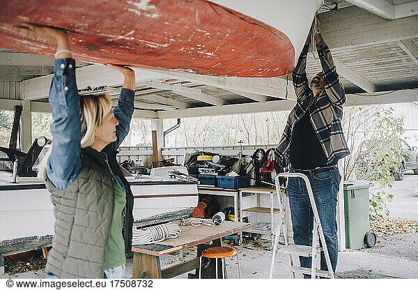 Mature man tying nautical vessel while female friend helping him in garage