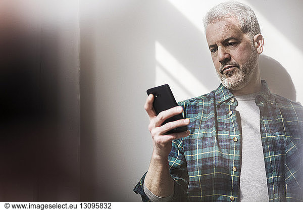 Mature man using smart phone at home