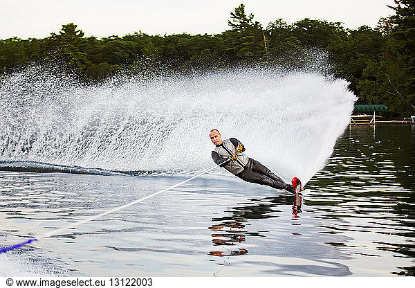 Mature man waterskiing in river against trees