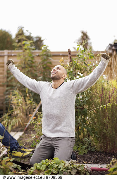 Mature man with arms outstretched in garden