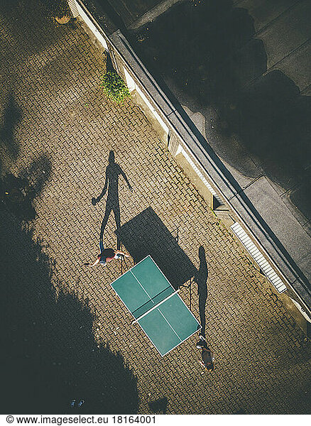 Mature man with daughter playing table tennis at back yard