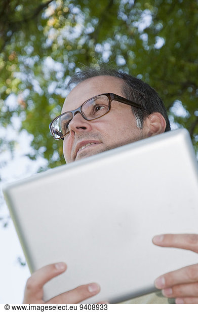 Mature man with digital tablet  looking away