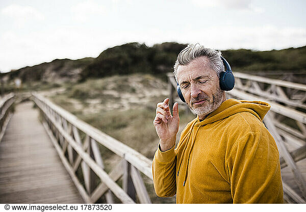 Mature man with eyes closed listening music through wireless headphones