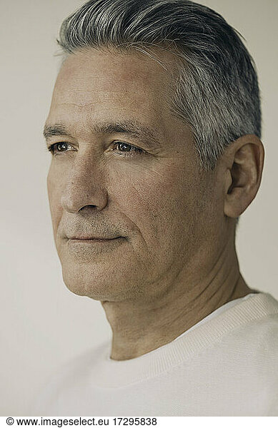 Mature man with gray hair against beige background