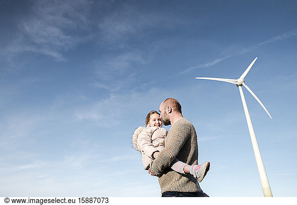 Mature man with his little daughter against sky