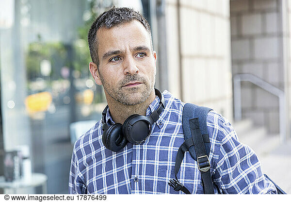 Mature man with wireless headphones wearing checked shirt