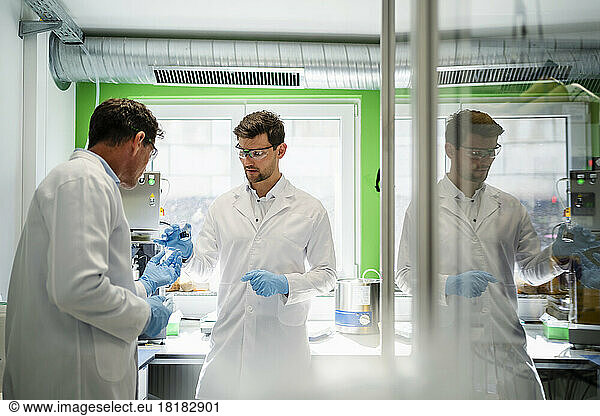 Mature scientist with colleague discussing over thermolysis experiment at laboratory