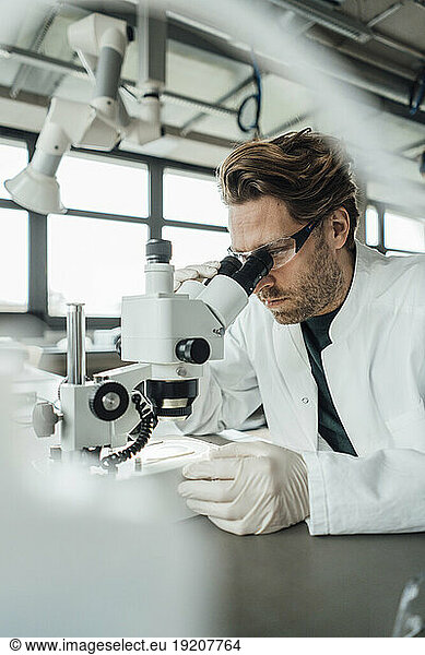 Mature scientist working on microscope in laboratory