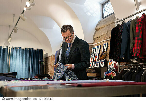 Mature tailor examining ornamental cloth