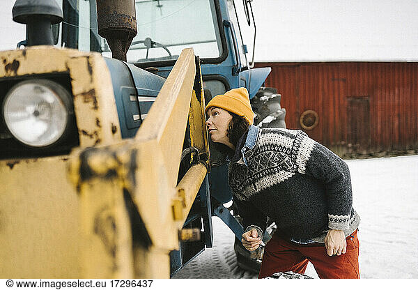 Mature woman analyzing tractor during winter