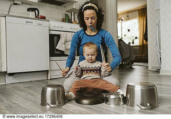 Mature woman and daughter playing with kitchen utensils at home