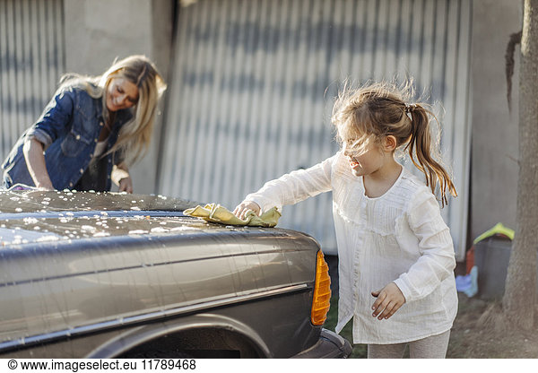 Mature woman and girl cleaning car together