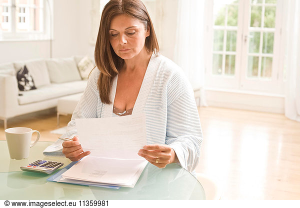 Mature woman at table reading bills