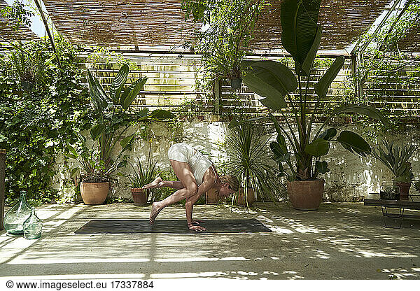 Mature woman balancing while doing yoga in garden
