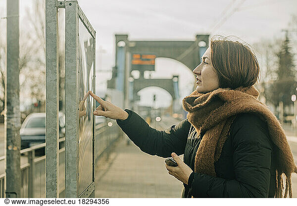Mature woman checking arrival departure board at tramway station