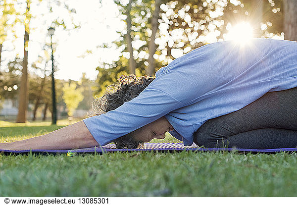 Mature woman doing yoga on grassy field