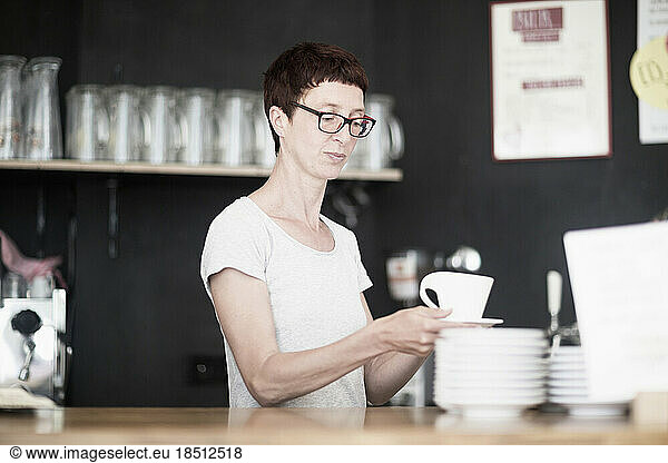 Mature woman drinking coffee in coffee shop  Freiburg im Breisgau  Baden-Württemberg  Germany