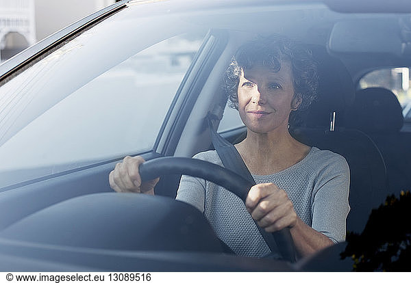 Mature woman driving car seen through windshield