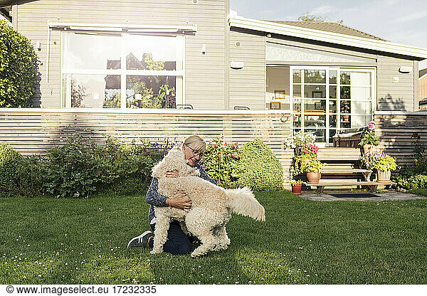 Mature woman embracing dog at front yard